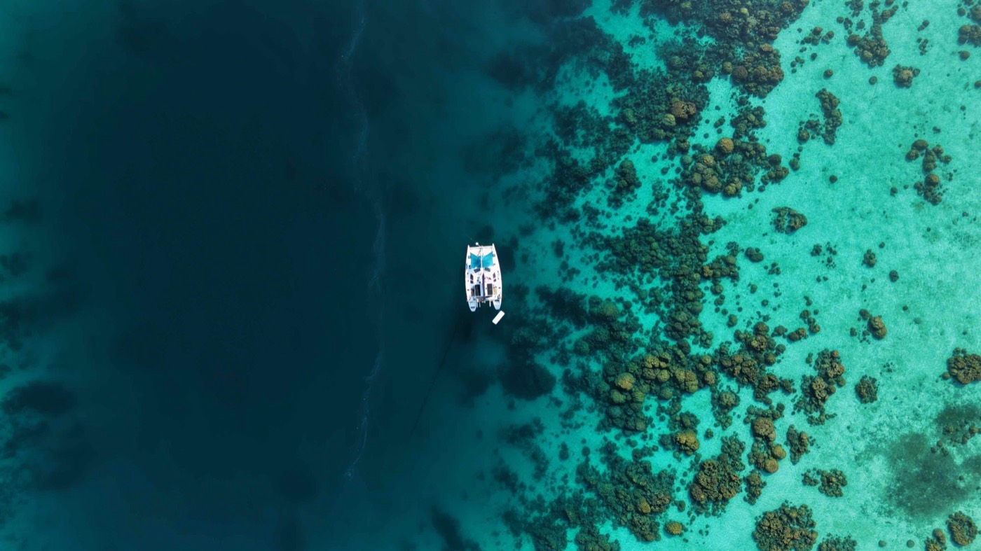 Catamaran at anchor at the edge of the reef, seen from above