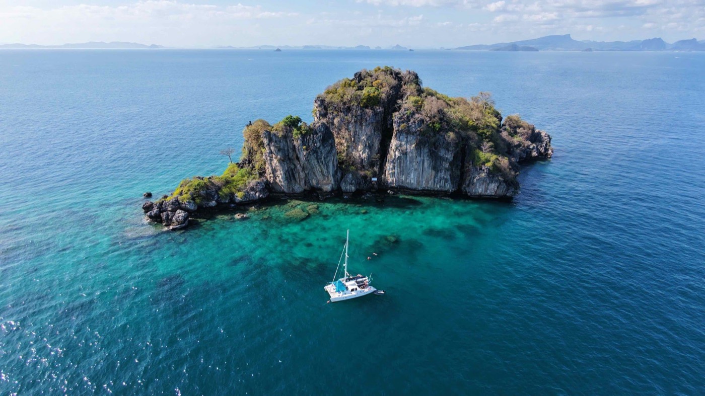 Catamaran at anchor in front of a limestone island