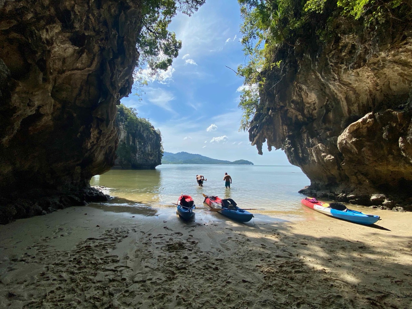 Kayaks on a beach under a limestone arch